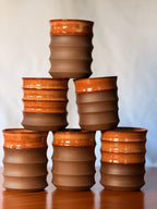 Pyramid stack of handmade stoneware water cups in rust glaze