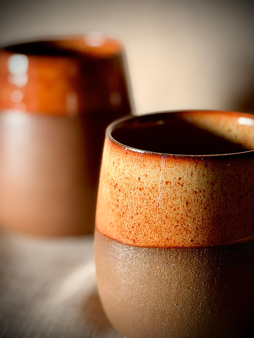 Detail of a handmade stoneware wine glass showing the rust glaze edge