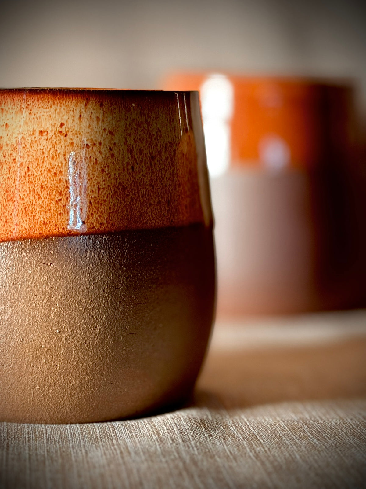 Close-up of a rust-glazed stemless wine glass in hand-thrown stoneware