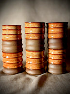 Columns of stacked handmade ceramic water cups in rust and grey glaze