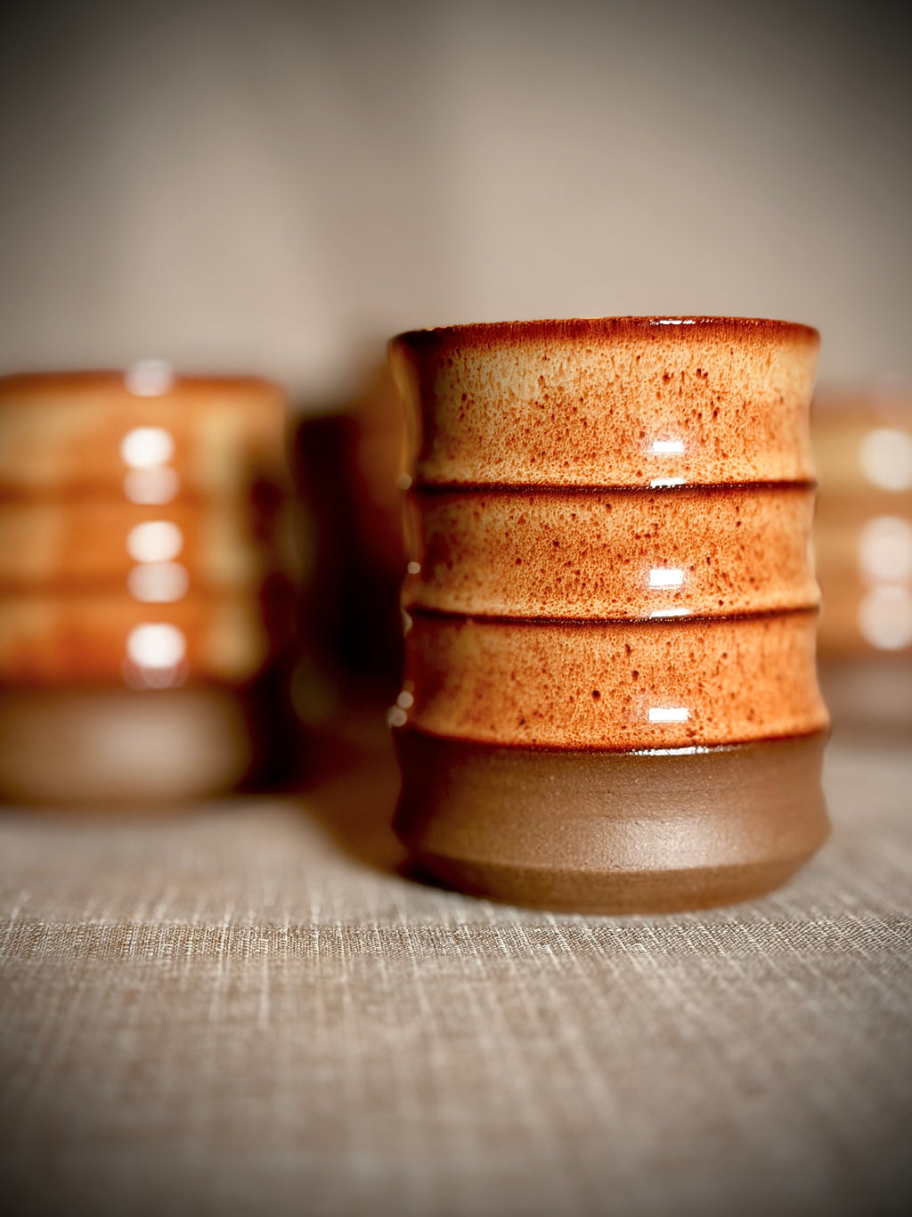 Handmade stoneware water cups in rust glaze on a wood table