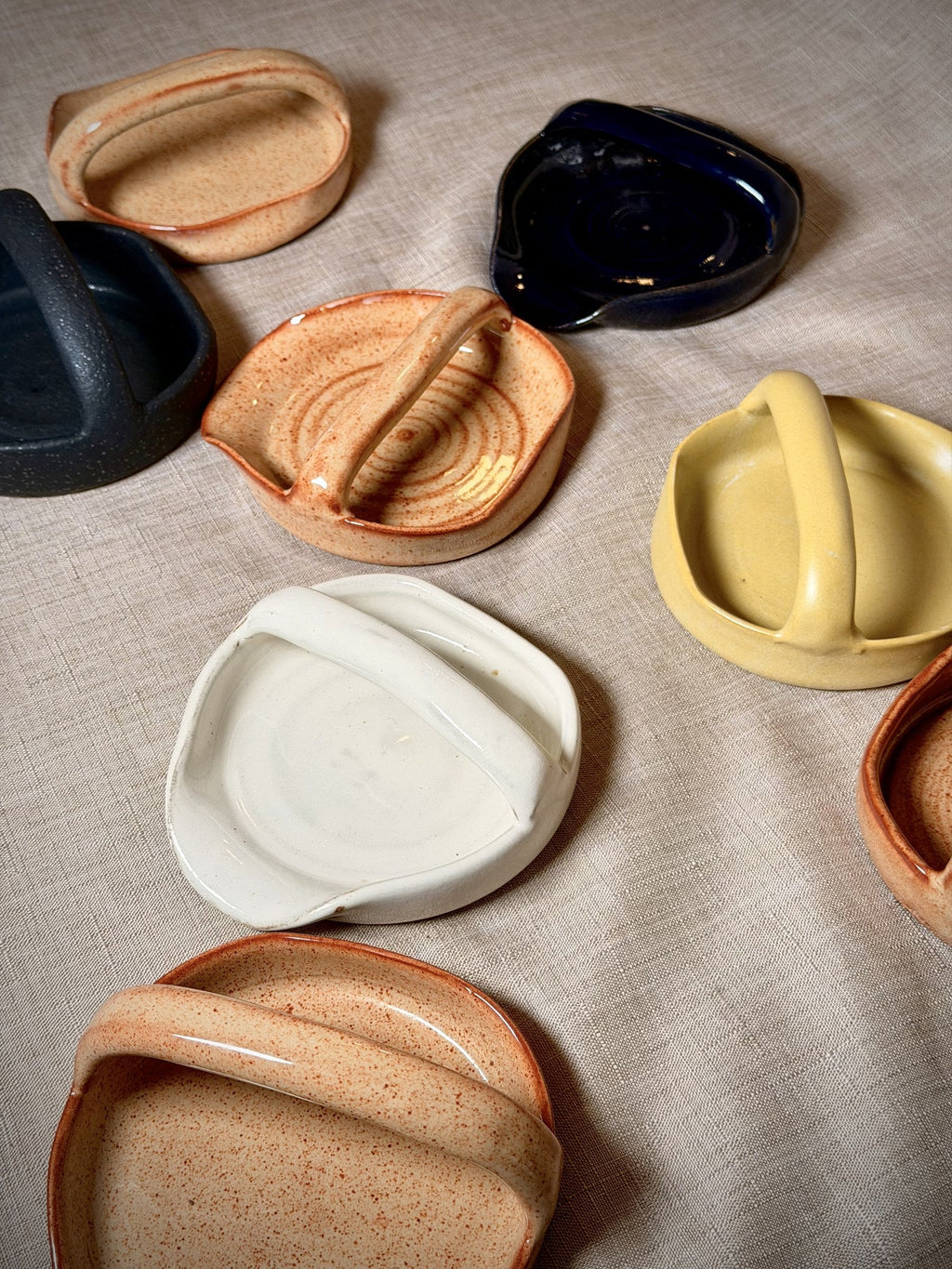 Hand-thrown stoneware spoon rests on linen